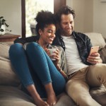 Shot of a happy young couple using a digital tablet while relaxing on a couch in their living room at home.